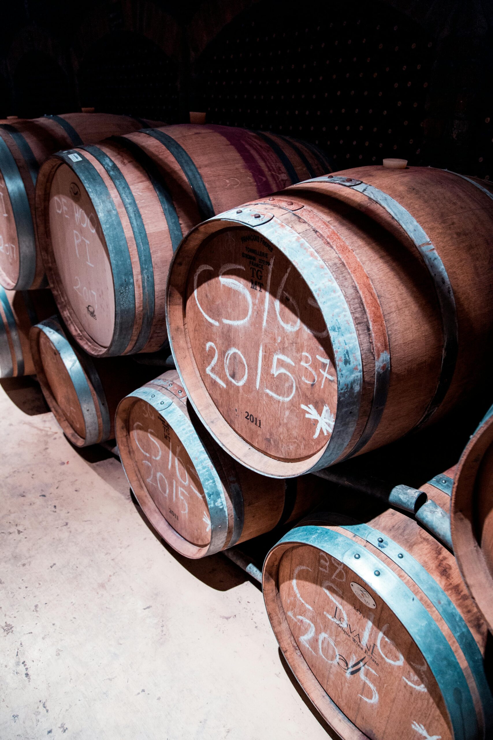 Wooden barrels aging wine in a Stellenbosch cellar, South Africa.